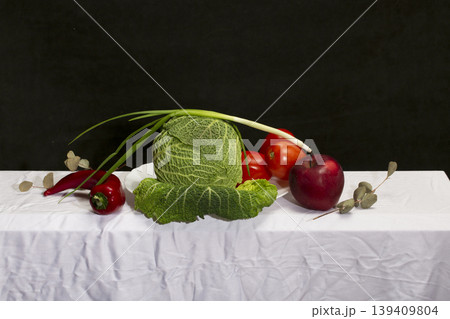 Still life with Savoy cabbage, vegetables and fruits on a white tablecloth 139409804