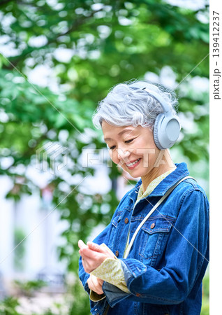 ヘッドフォンとスマホを操作するシニア女性 ヘッドフォンとスマホを操作するシニア女性 139412237