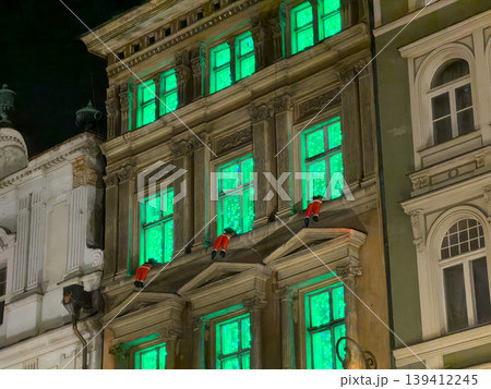 Ornate historic building showcasing bright green glowing windows and charming festive decorative figures, creating a mysterious holiday night display Ornate historic building showcasing bright green glowing windows and charming festive decorative figures, creating a mysterious holiday night display 139412245