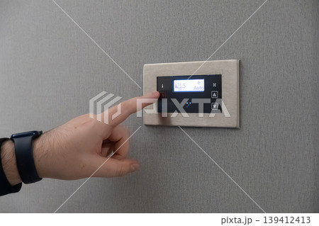 User adjusts modern digital thermostat, expertly managing smart home climate control for optimal comfort, energy efficiency, and intelligent living User adjusts modern digital thermostat, expertly managing smart home climate control for optimal comfort, energy efficiency, and intelligent living 139412413