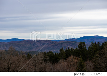 Vast mountain landscape showing layered forested hills under a soft cloudy sky, offering tranquil natural beauty for environmental themes and travel inspiration Vast mountain landscape showing layered forested hills under a soft cloudy sky, offering tranquil natural beauty for environmental themes and travel inspiration 139412559