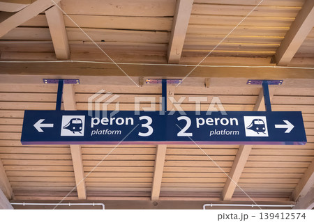 Blue direction sign under wooden ceiling, displaying peron 3 platform left and peron 2 platform right, guiding passengers' station navigation 139412574