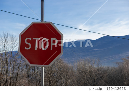 Vibrant red octagonal STOP sign prominently displayed on a pole against a clear blue sky, emphasizing vital traffic regulation and promoting essential road safety for drivers 139412628
