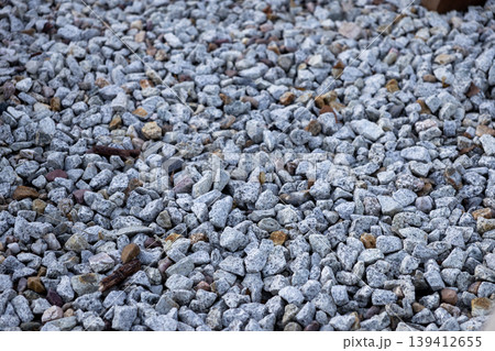 Detailed shot of natural gray and white gravel with an irregular rough surface, providing an abstract texture and earthy background for construction and landscape design Detailed shot of natural gray and white gravel with an irregular rough surface, providing an abstract texture and earthy background for construction and landscape design 139412655