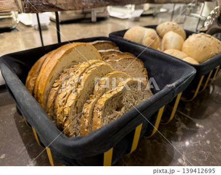 Freshly baked sliced bread and rolls displayed in baskets, offering a delicious variety for breakfast or a catered event, emphasizing healthy eating 139412695
