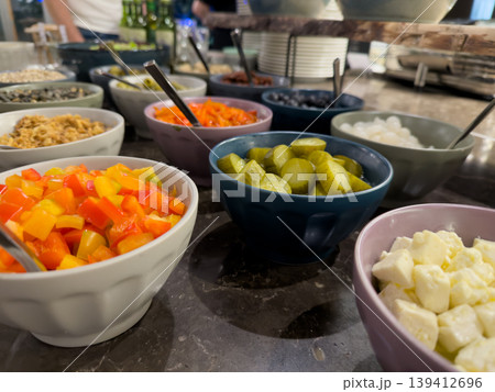 Colorful array of fresh ingredients in bowls on a buffet table, offering healthy, customizable meal options for catering events 139412696