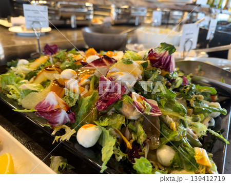 Fresh gourmet salad with mozzarella, fruit, and dressing, displayed elegantly at a luxurious hotel buffet for healthy catering services Fresh gourmet salad with mozzarella, fruit, and dressing, displayed elegantly at a luxurious hotel buffet for healthy catering services 139412719