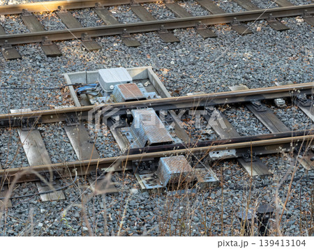A railroad switch machine mechanism installed on metal tracks with ballast stones represents essential infrastructure for transport safety, logistics, and train route navigation in industrial networks 139413104