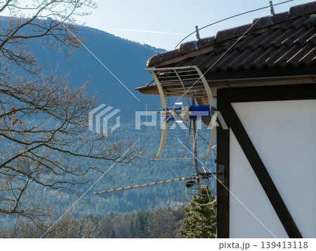 A television antenna is mounted on a rural house roof overlookin 139413118