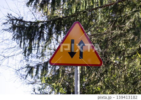 A two-way traffic road sign featuring opposite black arrows on a yellow triangular background, alerting all drivers to bidirectional vehicle movement on the street to enhance safety and compliance A two-way traffic road sign featuring opposite black arrows on a yellow triangular background, alerting all drivers to bidirectional vehicle movement on the street to enhance safety and compliance 139413182