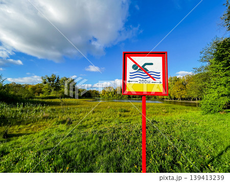 Sign on Bank of the lake is forbidden to swim on a summer day. Pointer that you can not swim here dirty water Sign on Bank of the lake is forbidden to swim on a summer day. Pointer that you can not swim here dirty water 139413239