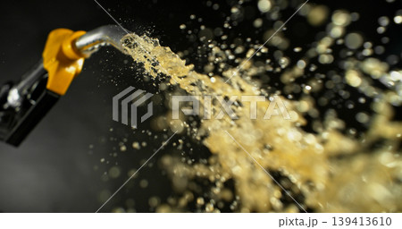 Gasoline jet spraying from fuel nozzle on dark background, no hand visible. Dynamic splash and droplets, refueling concept, energy supply, macro detail, dramatic lighting. 139413610