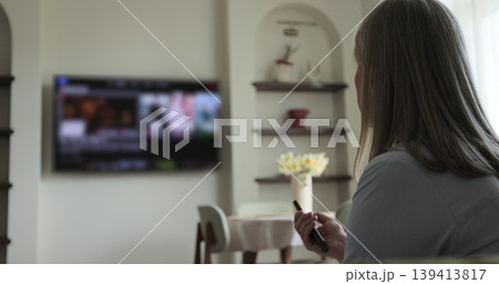 Senior woman selects tv channels with remote control at living room on sofa. Woman controls TV using a modern remote control. 139413817