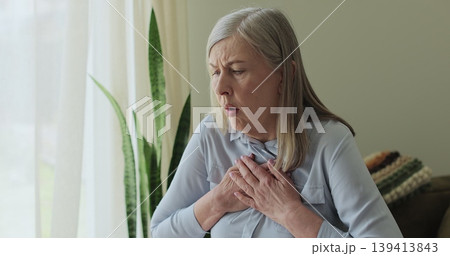 Senior woman, chest inflammation and cardiovascular emergency in lounge, panic attack and physical symptoms. 139413843