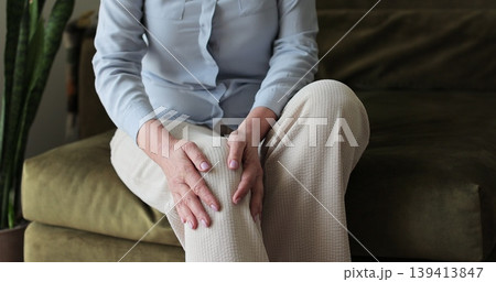Close-up elderly woman having pain in his knee in the home. Woman massages leg muscles, could not walk, rheumatism. Close-up elderly woman having pain in his knee in the home. Woman massages leg muscles, could not walk, rheumatism. 139413847