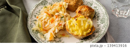 Two plates hold baked potato baskets filled with creamy filling, turkey meatballs, and fermented cabbage, served at a simple dining table setting during a meal, banner Two plates hold baked potato baskets filled with creamy filling, turkey meatballs, and fermented cabbage, served at a simple dining table setting during a meal, banner 139413916