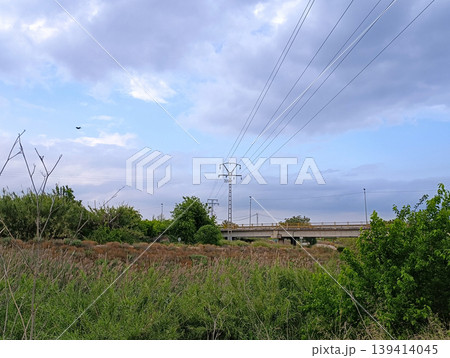 Power Line Structure in Natural Landscape with Bridge in Background Power Line Structure in Natural Landscape with Bridge in Background 139414045