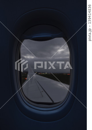 Plane wing with blurred airport lights at night seen through airplane window Plane wing with blurred airport lights at night seen through airplane window 139414836
