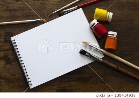 Top view of sketchbook with paint brushes and paint tubes on wooden table with copy space Top view of sketchbook with paint brushes and paint tubes on wooden table with copy space 139414938