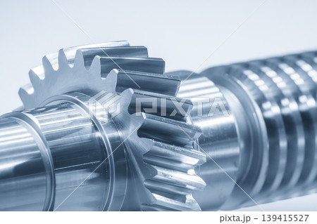 Close-up of high-precision bevel gear parts mounted on a transmission gear shaft in a blue-toned industrial scene. Close-up of high-precision bevel gear parts mounted on a transmission gear shaft in a blue-toned industrial scene. 139415527