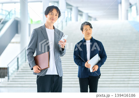 スマホとファイルを持つ30代男性と50代男性のビジネスシーン 139416186