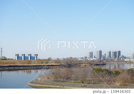 広大な空と青い水門の風景 穏やかな川の流れと遠くのビル群が調和する都会の静寂な日常 広大な空と青い水門の風景 穏やかな川の流れと遠くのビル群が調和する都会の静寂な日常 139416305