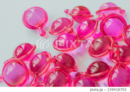 Close-up macro shot of many glossy pink hair treatment capsules. Focused foreground highlights the rich oil and reflective texture Close-up macro shot of many glossy pink hair treatment capsules. Focused foreground highlights the rich oil and reflective texture 139416701