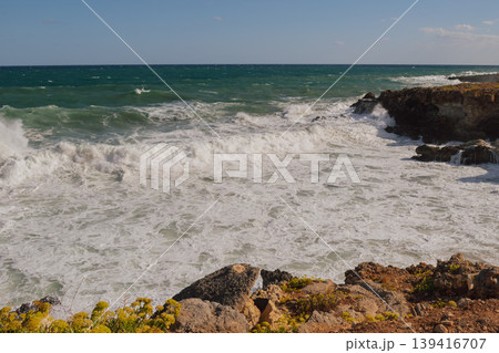Powerful surf hitting rocks emerald blue sea white foam and clear sky. 139416707
