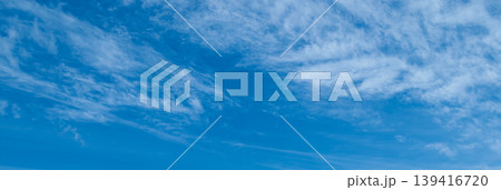 Panoramic view of a clear azure sky with wispy cirrus clouds. Soft blue gradients and airy textures create a vast minimalist backdrop with extensive copy space for web Panoramic view of a clear azure sky with wispy cirrus clouds. Soft blue gradients and airy textures create a vast minimalist backdrop with extensive copy space for web 139416720