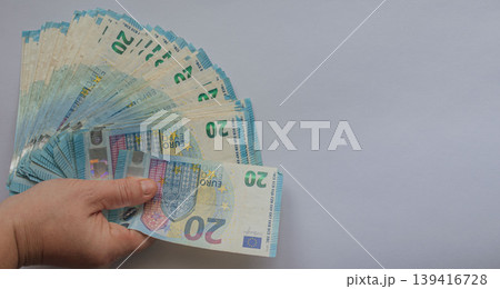 Female hand holding a large fan of 20 Euro banknotes against a white background. Vivid blue currency concept with extensive copy space for financial or business text Female hand holding a large fan of 20 Euro banknotes against a white background. Vivid blue currency concept with extensive copy space for financial or business text 139416728