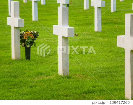 Crosses stand in a row as flowers sit at a grave in a cemetery where people remember their loved ones 139417260