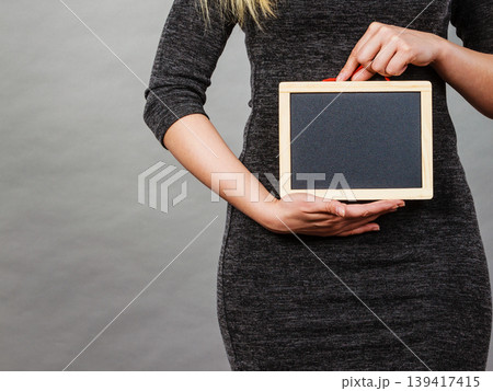 Woman holding blank black board on stomach 139417415