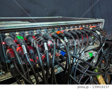 A complex array of colorful cables intricately connected to a professional audio mixer in a recording studio. A complex array of colorful cables intricately connected to a professional audio mixer in a recording studio. 139418137