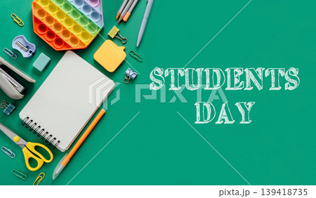 Colorful stationery and supplies arranged on green background for Students Day celebration Colorful stationery and supplies arranged on green background for Students Day celebration 139418735
