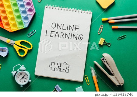 Online learning concept with stationery items and colorful educational tools on green background 139418746