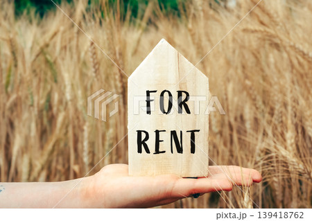 Hand holding wooden sign with text for rent in a field of golden wheat and natural background Hand holding wooden sign with text for rent in a field of golden wheat and natural background 139418762