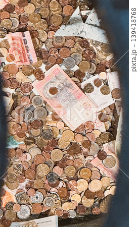 Pile of assorted coins and banknotes in a container showcasing currency diversity and value 139418768