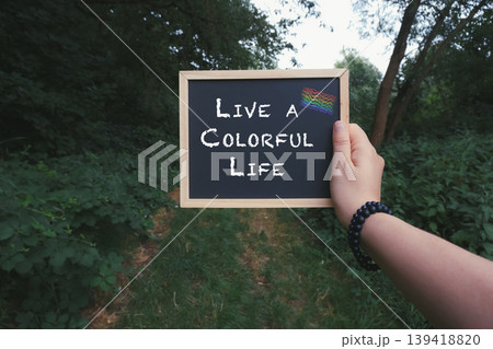 Person holding a chalkboard with the words Live a colorful life Person holding a chalkboard with the words Live a colorful life 139418820