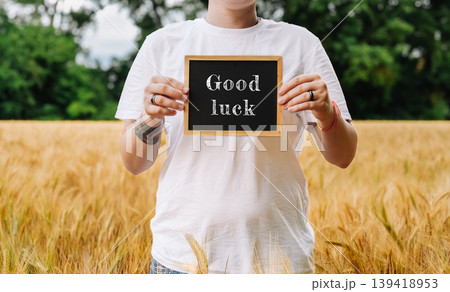 Person holding a chalkboard with the word good luck written on it Person holding a chalkboard with the word good luck written on it 139418953