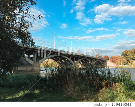 Bridge spans a river with a green and brown grassy area on either side Bridge spans a river with a green and brown grassy area on either side 139419041