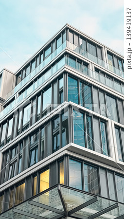 Modern architectural building with glass facade and geometric design elements showcasing urban style Modern architectural building with glass facade and geometric design elements showcasing urban style 139419137