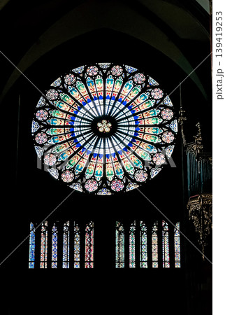Stunning stained glass rose window featuring intricate patterns and vibrant colors, illuminating the interior space with a spiritual ambiance Stunning stained glass rose window featuring intricate patterns and vibrant colors, illuminating the interior space with a spiritual ambiance 139419253
