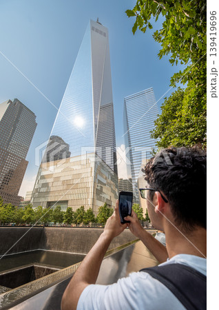 New york, usa august 17,2024. Tourist exploring downtown manhattan, capturing the modern architecture of the one world trade center and reflecting on the 911 memorial New york, usa august 17,2024. Tourist exploring downtown manhattan, capturing the modern architecture of the one world trade center and reflecting on the 911 memorial 139419696