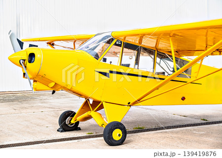 A yellow single-engine ultralight aircraft on the airfield runway. A yellow single-engine ultralight aircraft on the airfield runway. 139419876