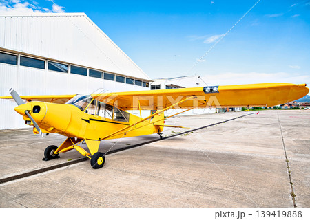 A yellow single-engine ultralight aircraft on the airfield runway. A yellow single-engine ultralight aircraft on the airfield runway. 139419888