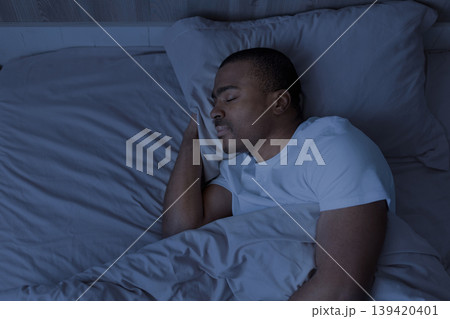 Peaceful African american man sleeping at night in bed Peaceful African american man sleeping at night in bed 139420401