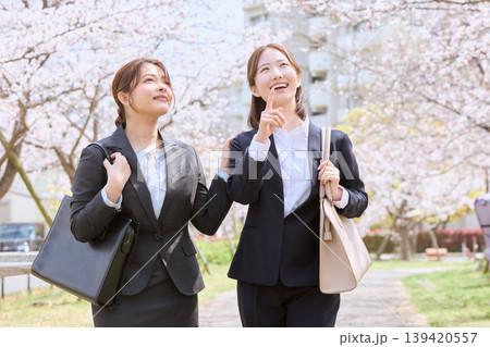 桜並木の下を歩く二人の若い女性ビジネスパーソン・新入社員のスーツ姿で春の通勤風景 桜並木の下を歩く二人の若い女性ビジネスパーソン・新入社員のスーツ姿で春の通勤風景 139420557