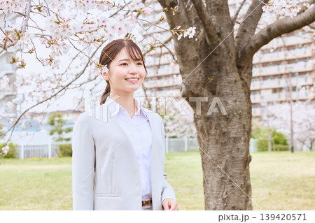 桜の木の下で微笑む新入社員の若い女性・春のフレッシャーズイメージ・スーツ姿のビジネスウーマン 139420571
