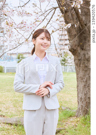 桜の下で微笑む白スーツの若い女性・春の新生活イメージ・新入社員のフレッシュなビジネスウーマン 桜の下で微笑む白スーツの若い女性・春の新生活イメージ・新入社員のフレッシュなビジネスウーマン 139420576