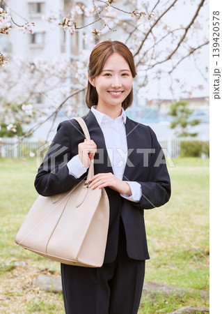 桜の下で微笑むリクルートスーツ姿の若い女性・春の就職活動イメージ 桜の下で微笑むリクルートスーツ姿の若い女性・春の就職活動イメージ 139420578